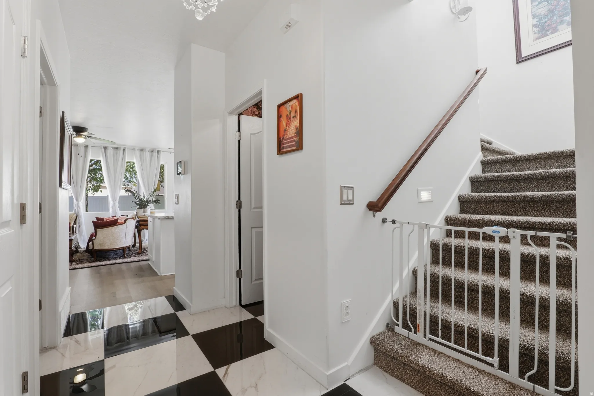 Black and white checkered tile flooring, carpeted staircase with wood handrail, and white walls