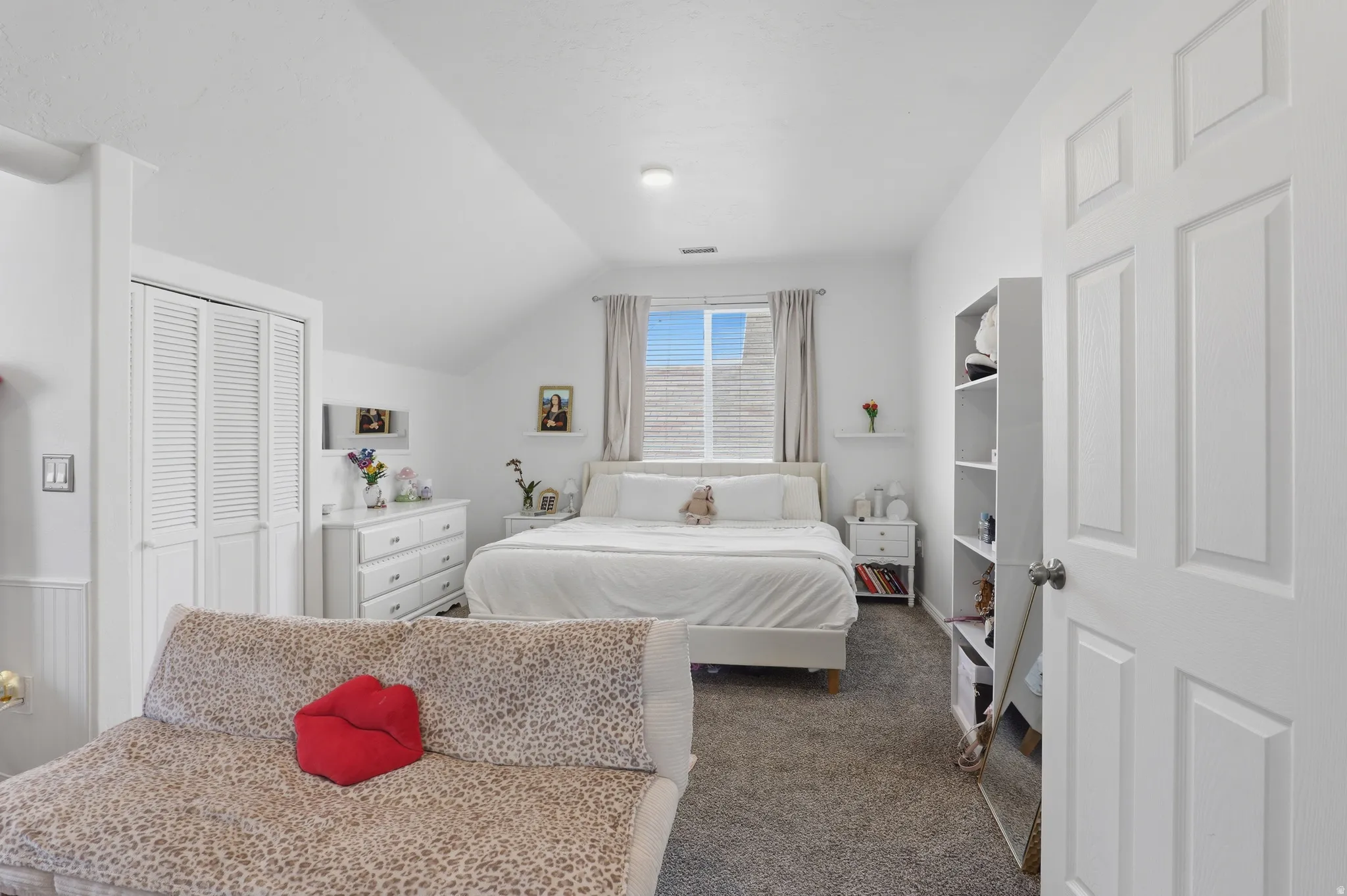 Carpeted flooring with white paneled walls and a sloped ceiling