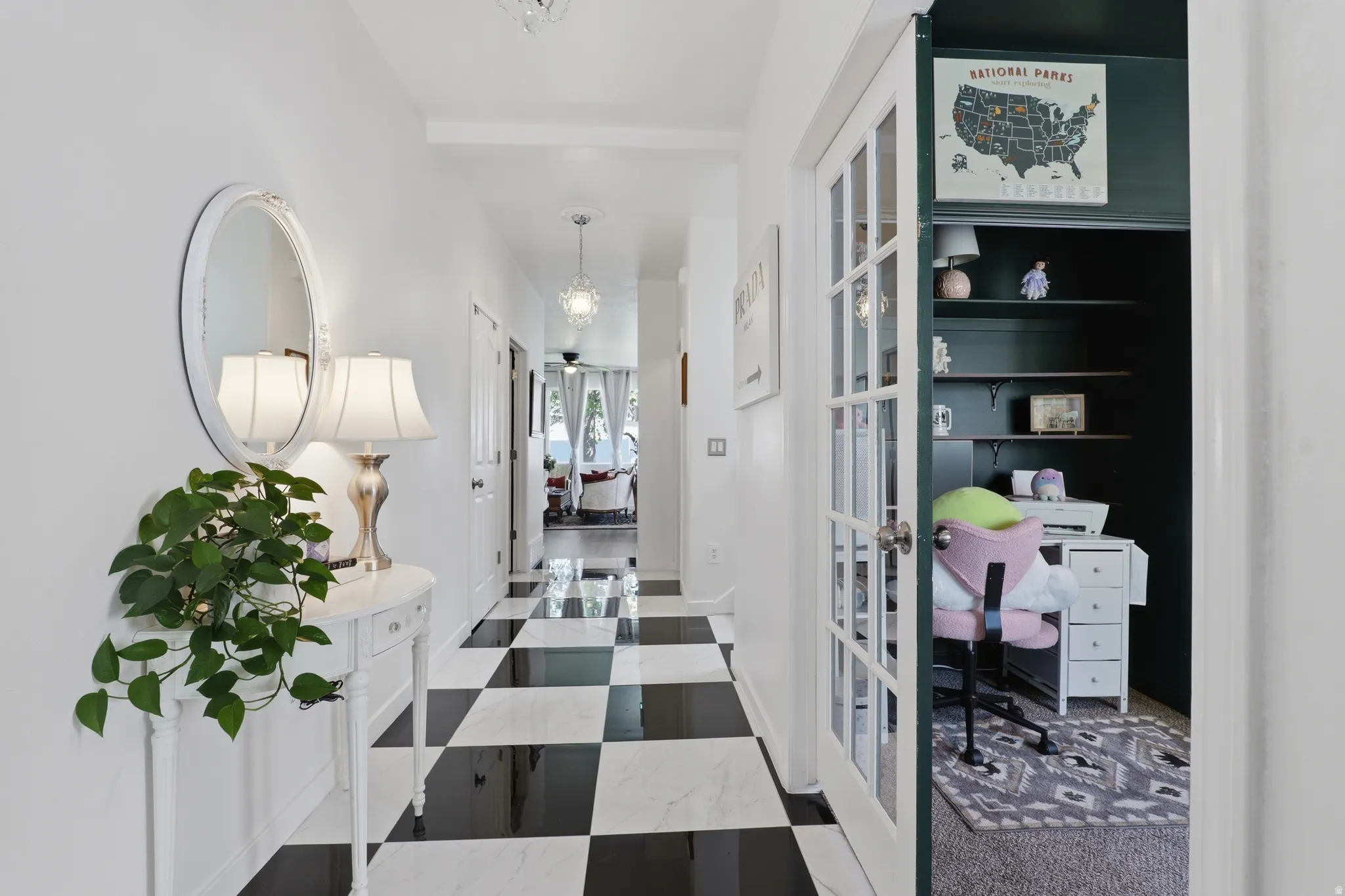 Hallway featuring black and white checkered flooring, white walls, and a recessed office space with built-in shelving