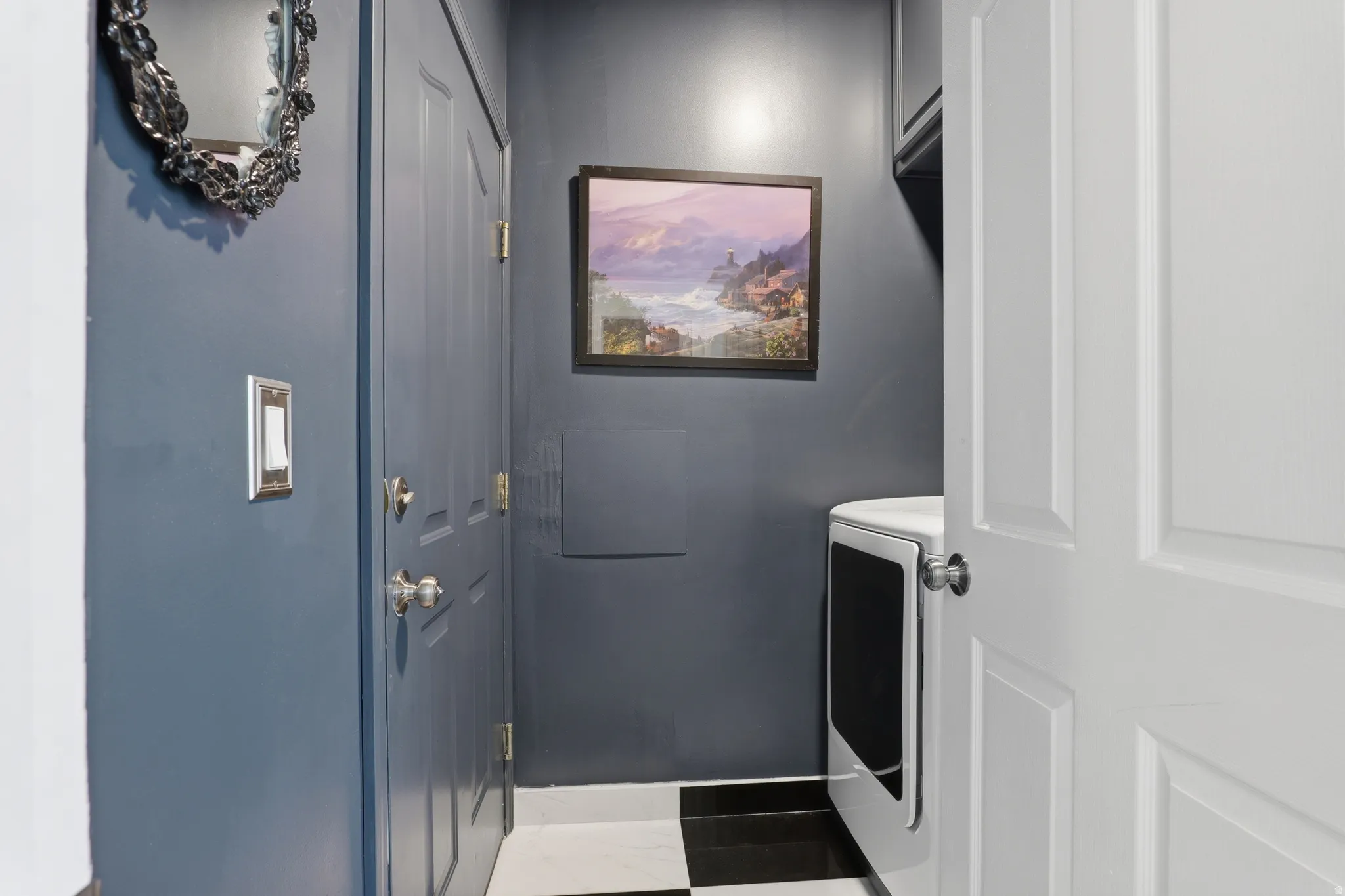 White paneled door with a round silver-tone knob, dark gray painted walls, and a black and white checkered floor