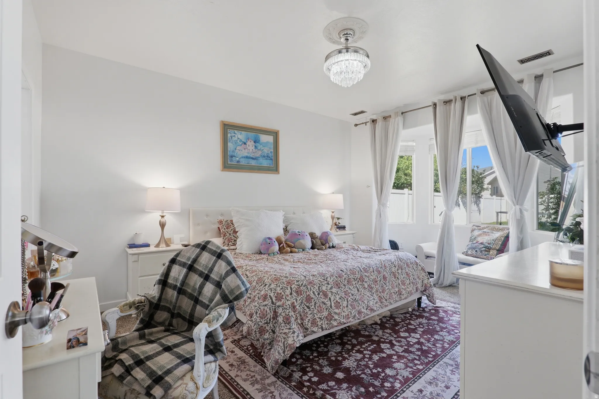 White walls with a crystal-style ceiling light fixture, framed windows, and a decorative area rug