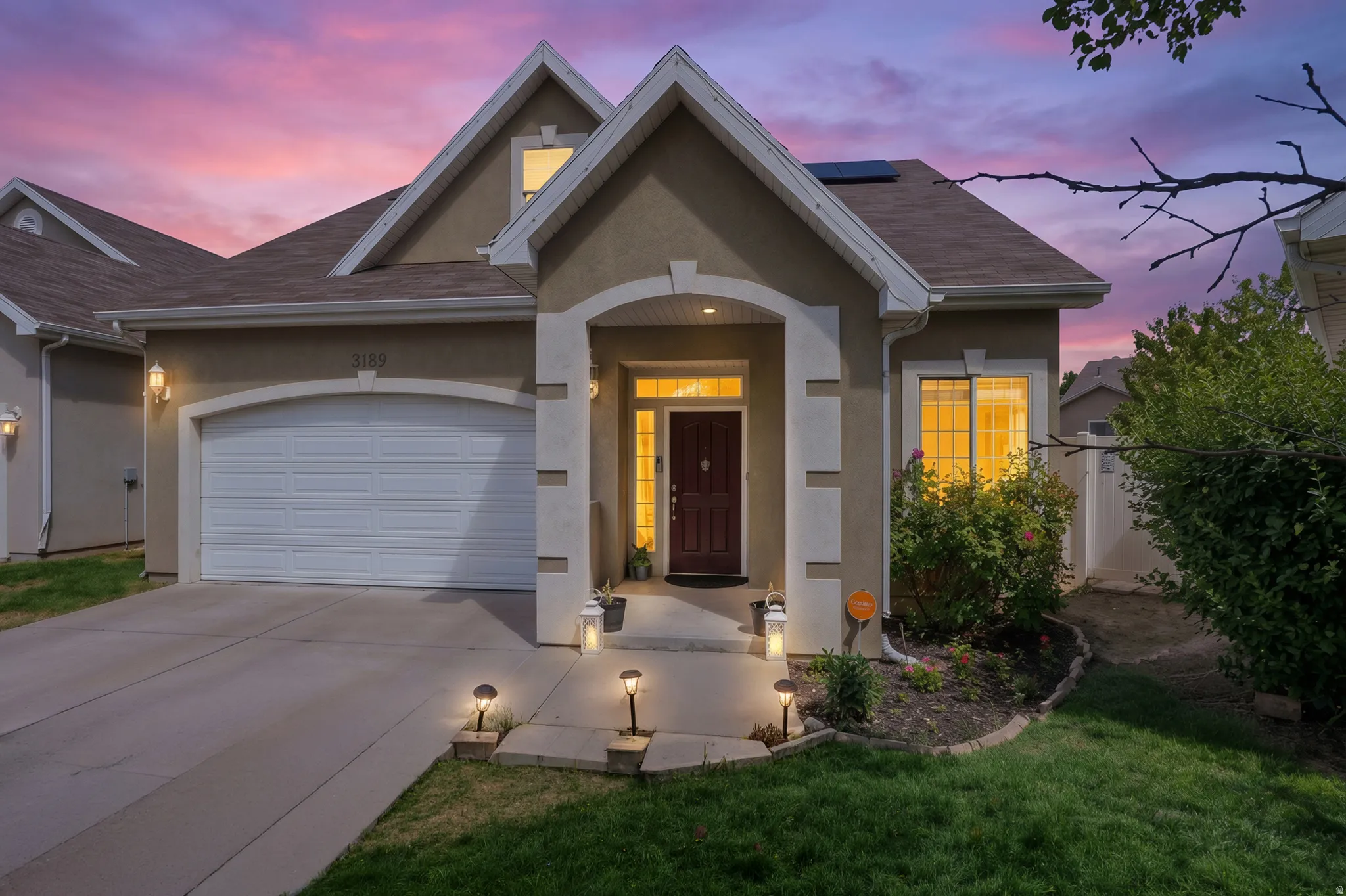 Stucco exterior with an arched entry, attached garage, and a concrete driveway