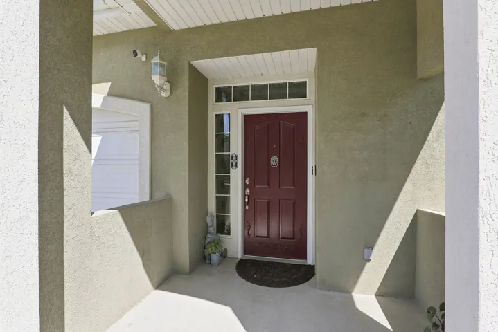 Stucco exterior with a paneled front door, transom window, and sidelight