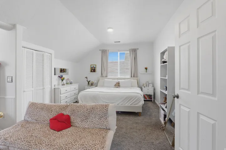 Carpeted flooring with white paneled walls and a sloped ceiling