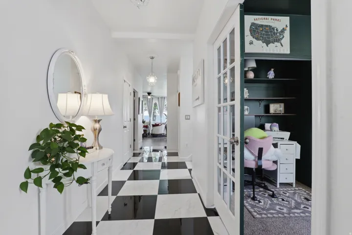 Hallway featuring black and white checkered flooring, white walls, and a recessed office space with built-in shelving