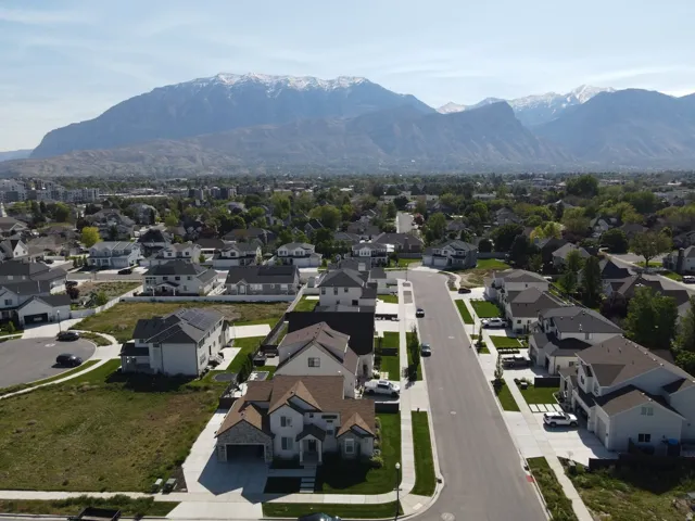 Residential neighborhood featuring a paved street, established trees, and mountain scenery