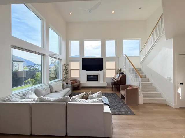 Vaulted ceilings with recessed lighting, expansive windows, wood-finish flooring, a contemporary fireplace, and a staircase with white balusters