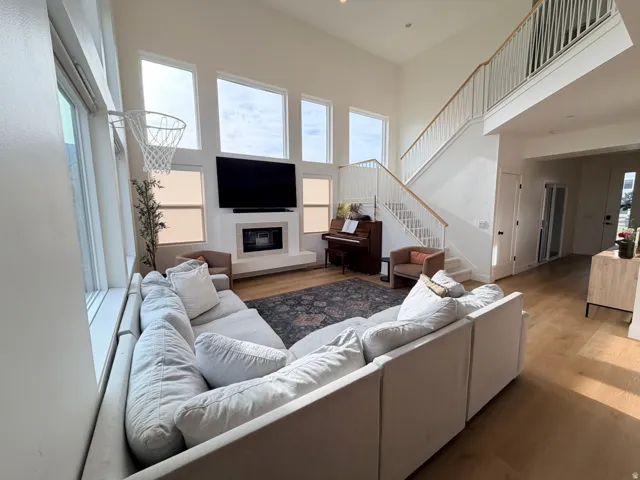 Two-story living area with high ceilings, multiple large windows, a built-in fireplace, and wood-finish flooring