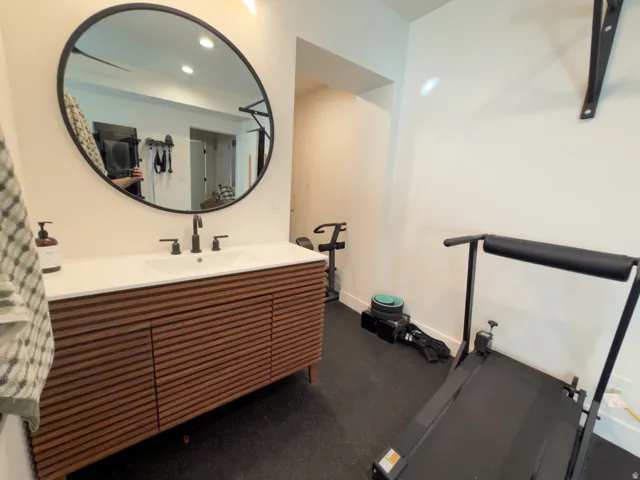 Wood-finish vanity with slat detailing, white countertop, and integrated rectangular sink