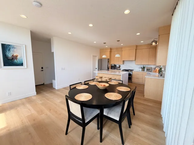 Open-concept kitchen and dining area featuring light wood-finish flooring, recessed lighting, and a modern kitchen with a white quartz countertop island