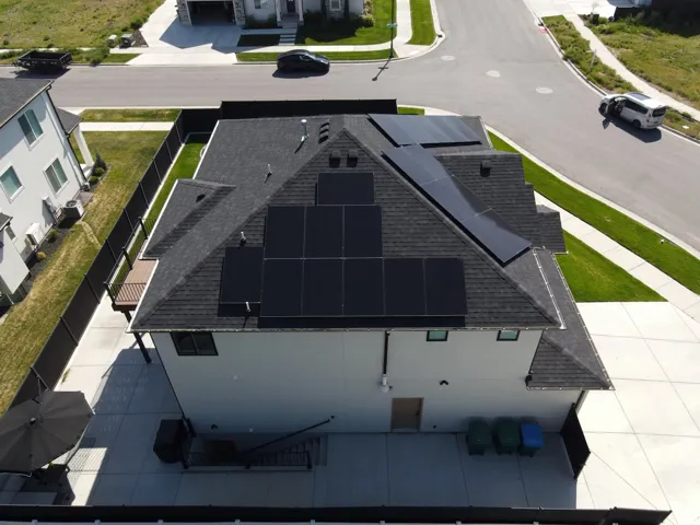 Architectural roof with integrated solar panels, concrete patio, and a privacy fence