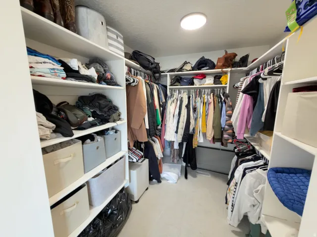 Integrated closet organization system featuring white shelving and hanging rods