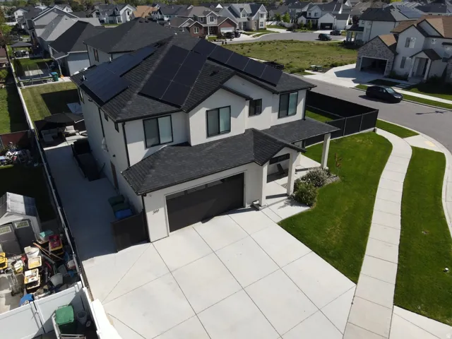Two-story stucco exterior with a dark shingle roof and integrated solar panels