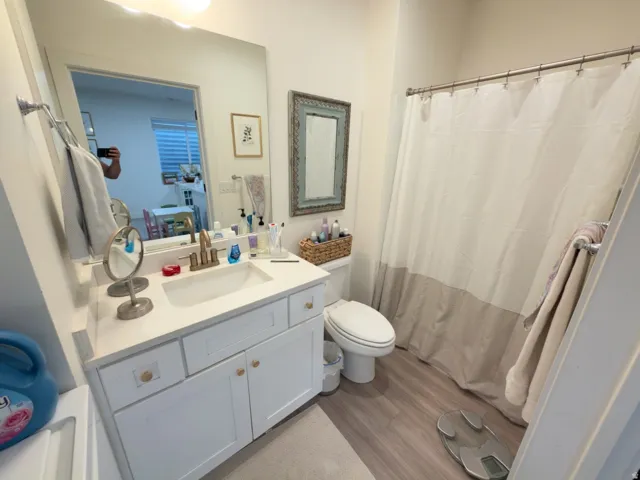 White vanity with a solid surface countertop, rectangular undermount sink, and brushed brass-finish faucet