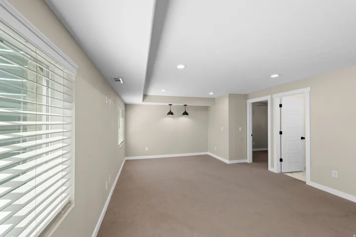 Recessed lighting, neutral-toned walls, and carpeted flooring