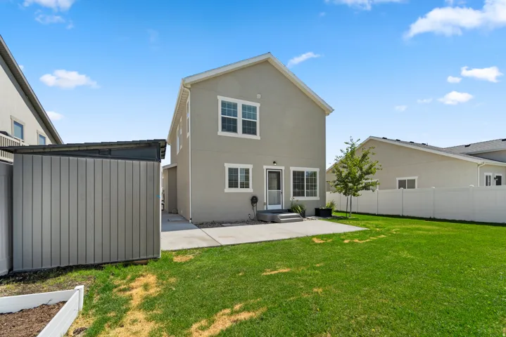 Expansive green lawn, concrete patio, privacy fencing, and mature landscaping. The shed has been removed