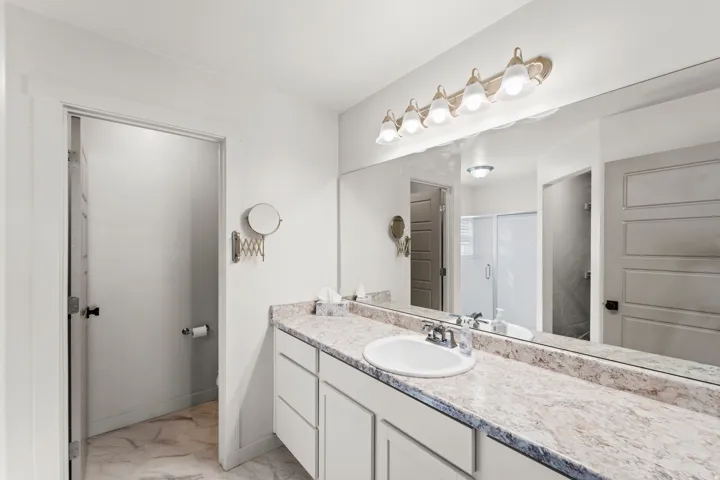 Vanity featuring a single undermount sink, dual handle faucet, and speckled stone countertop