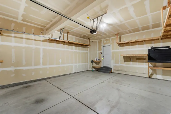 Concrete flooring with ceiling-mounted garage door opener and integrated shelving