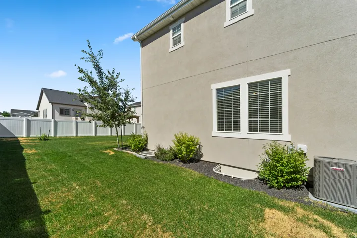 Expansive backyard featuring a manicured lawn, established shrubs, and privacy fencing