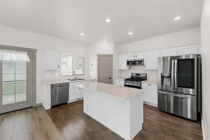 Kitchen featuring wood-finish flooring, white cabinetry, a central island, stainless steel appliances, and recessed lighting