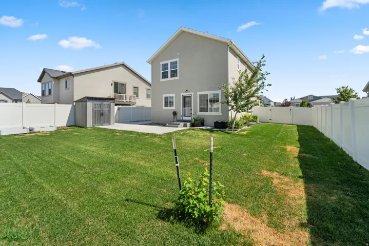 Expansive backyard featuring a manicured lawn, concrete patio, and privacy fencing. The shed has been removed