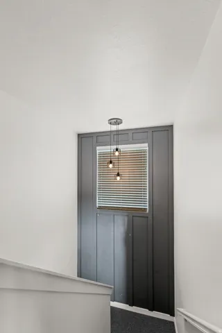 Modern pendant light fixture, window with blinds, and dark board and batten accent wall