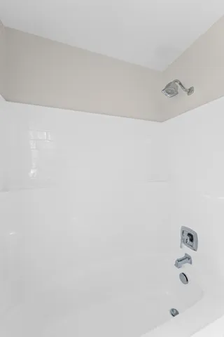 White subway tile shower surround with integrated tub, chrome showerhead, and coordinating bath fixtures