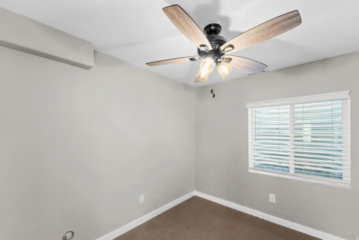 Ceiling fan with integrated lighting, window with blinds, light gray wall finish, and brown carpet flooring
