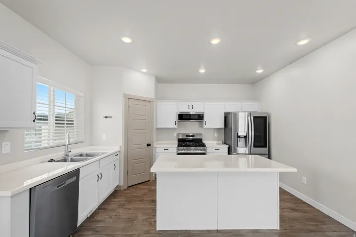 Kitchen featuring white cabinetry, light-toned countertops, a stainless steel appliance package, and wood-finish flooring
