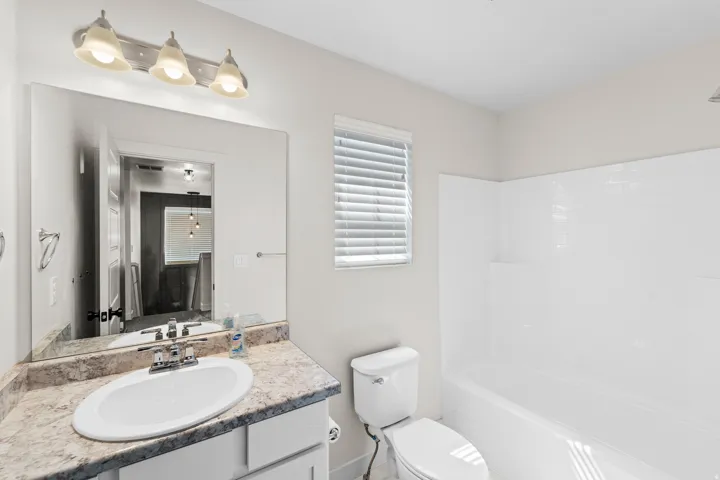 White bathroom vanity with an oval undermount sink, chrome faucet, and a large wall-mounted mirror