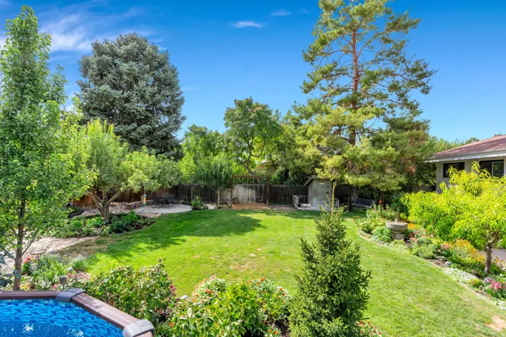 Expansive backyard featuring a manicured lawn, established trees, and mature landscaping
