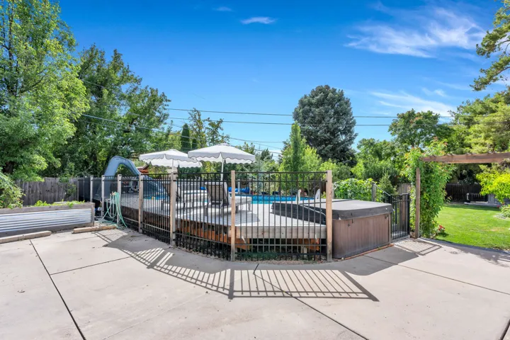 Concrete patio area, fenced swimming pool, raised spa, wood deck surround, and pergola