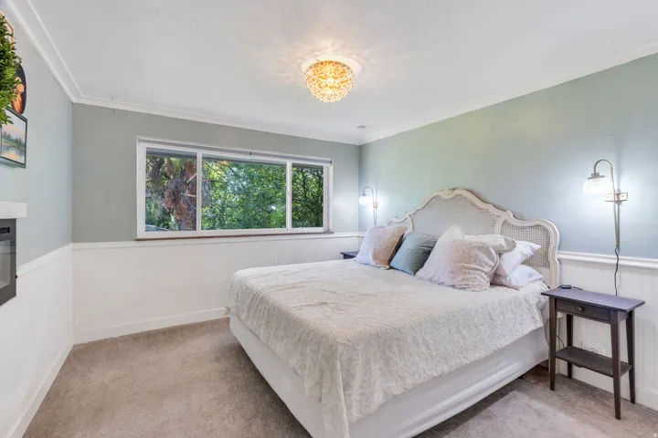 Wall-mounted fireplace, multi-pane window, beadboard wainscoting, crown molding, and a decorative ceiling light fixture