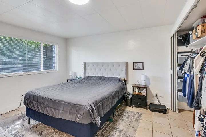 Recessed window with blinds, white walls, built-in shelving, tiled flooring, and a ceiling-mounted light fixture