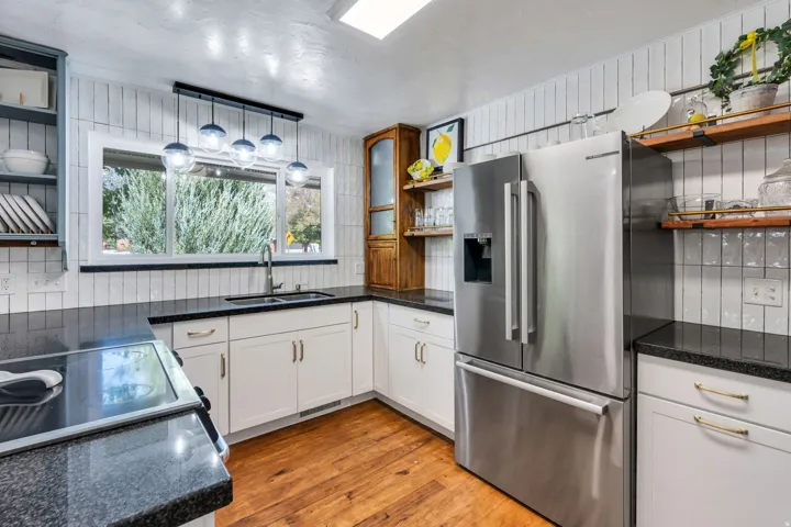 Kitchen featuring wood-finish flooring, white cabinetry, black countertops, and stainless steel appliances