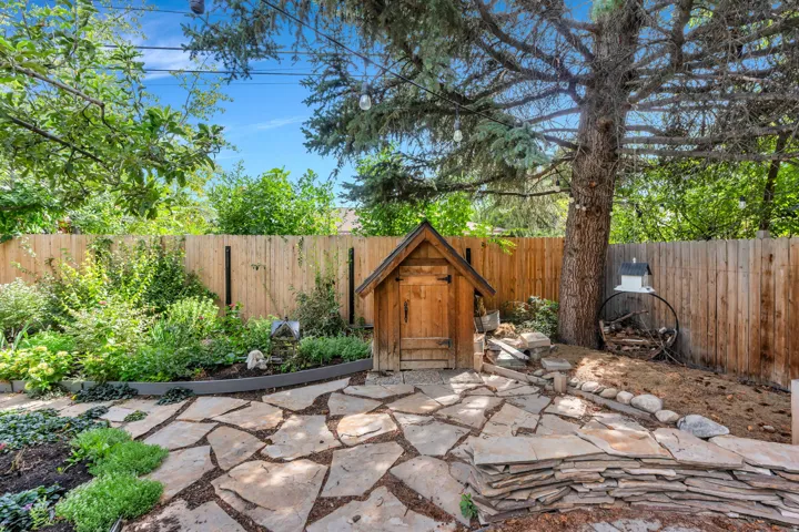 Stone patio with irregular flagstone pavers, surrounded by mature trees and varied plantings