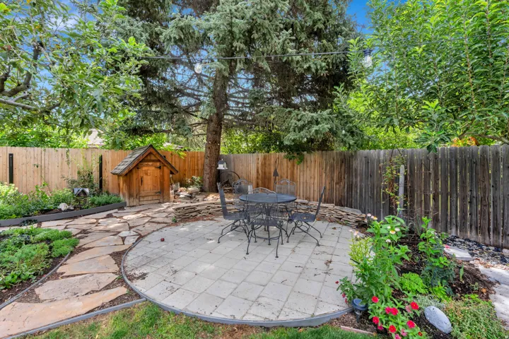 Expansive backyard featuring a paver patio, flagstone pathway, mature trees, and a privacy fence