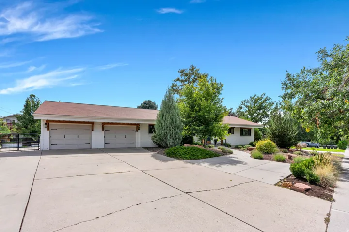 Concrete driveway, attached two-car garage, mature landscaping, decorative exterior lighting, and a composite shingle roof