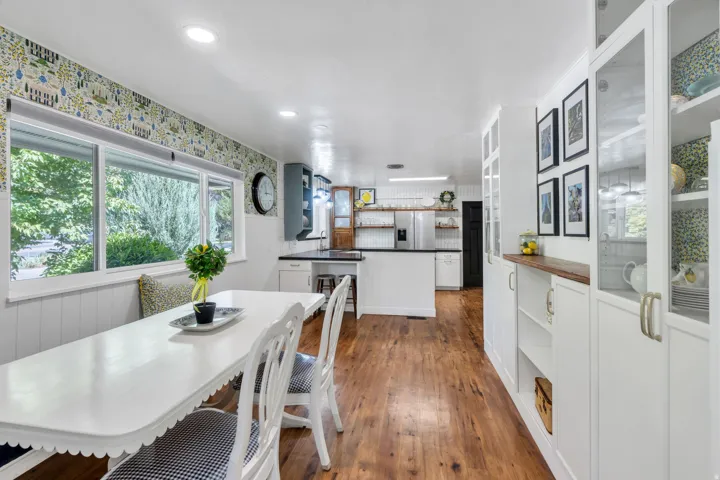 Wood-finish flooring throughout, white base cabinetry with contrasting countertops, recessed lighting, and built-in shelving with glass-front uppers
