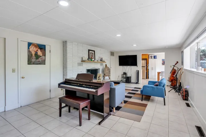 Spacious room featuring tile flooring, a white painted brick fireplace, recessed lighting, and ample natural light from multiple windows