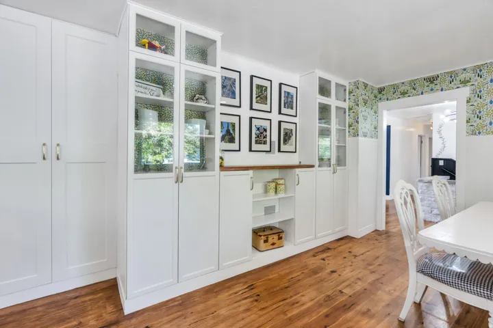 Built-in cabinetry with glass-front display cabinets, hardwood flooring, and wainscoting