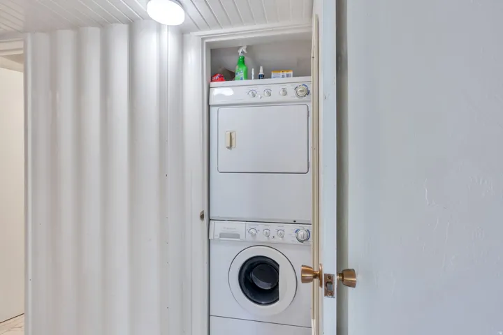 Stackable washer and dryer unit, integrated storage shelving, and overhead lighting