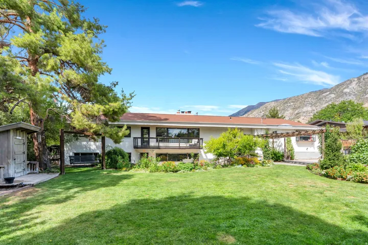 Expansive green lawn with mature trees and mountain backdrop