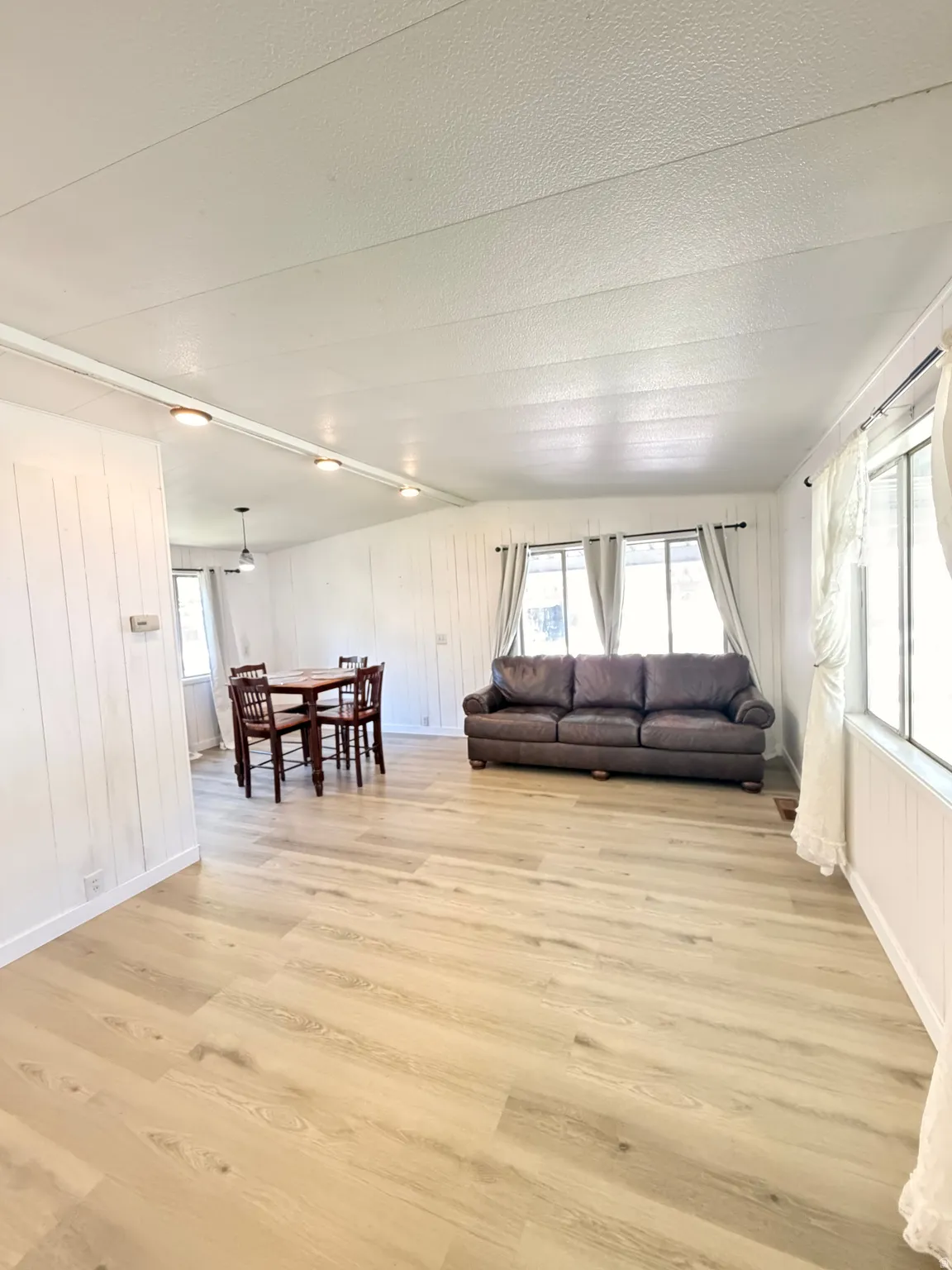 Wood-finish flooring throughout, white paneled walls, and multiple windows