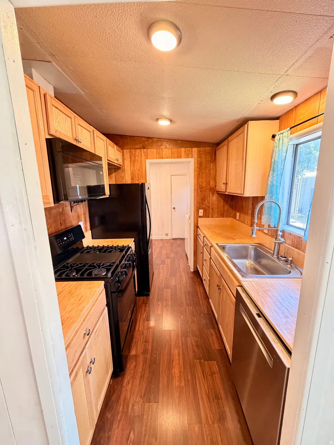 Galley kitchen featuring wood-finish flooring, wood cabinetry, and wood countertops