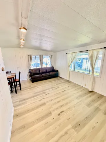 Bright interior featuring light wood-finish flooring, white paneled walls, and multiple windows
