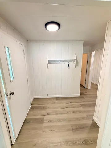 Wood-finish flooring, vertical paneling, and an overhead flush-mount light fixture