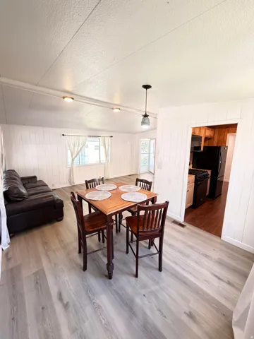 Light wood-finish flooring throughout, white paneled walls, recessed ceiling lighting, and a pendant light fixture