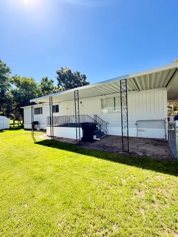 Expansive lawn area with a covered patio featuring decorative metal columns and railings