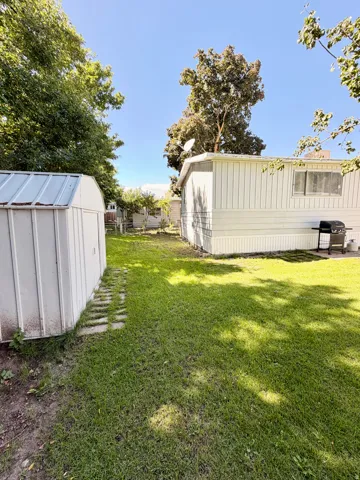 Expansive lawn area featuring a storage shed and mature trees
